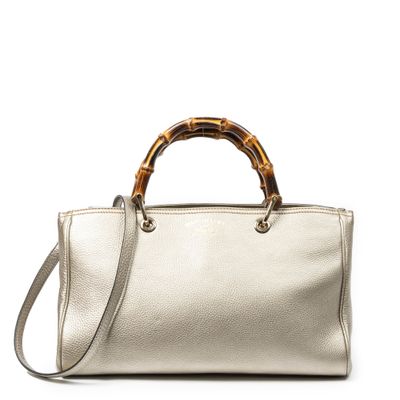 un sac à main blanc muni d'une poignée en bambou, sur fond blanc