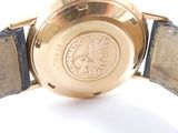 a gold watch with a black leather band on a white surface