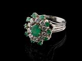 an emerald and diamond cluster ring on a black surface