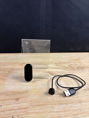 a small black object sitting on a table next to a charger