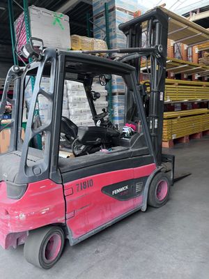 a red fork truck parked in a warehouse with pallets