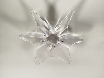 une décoration en forme d'étoile en verre transparent posée sur une table blanche