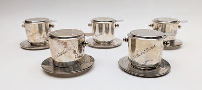 six tasses et soucoupes plaquées argent sur un fond blanc