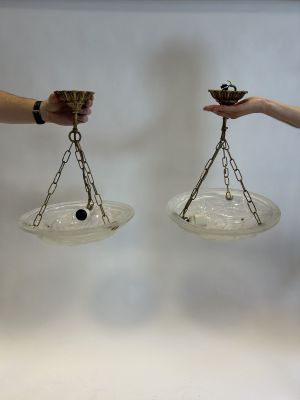 two hands holding a pair of glass bowls with chains
