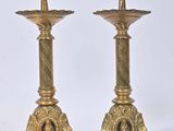 pair of antique brass candlesticks on pedestals against a white background