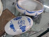 three blue and white porcelain objects on display in a glass case