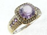 a close up of a ring with a purple stone surrounded by diamonds