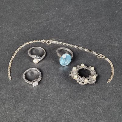 trois bagues et un collier posés sur une table, avec une chaîne