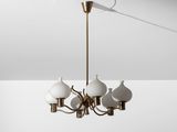 un lustre en laiton muni de cinq abat-jours en verre blanc suspendu au plafond