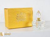 a small glass perfume bottle sitting next to a gold box