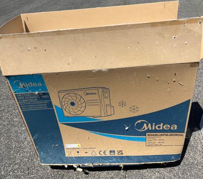 une boîte en carton posée par terre, avec un ventilateur à l'intérieur