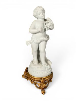 une figurine blanche représentant un garçon tenant un chien, posée sur un socle