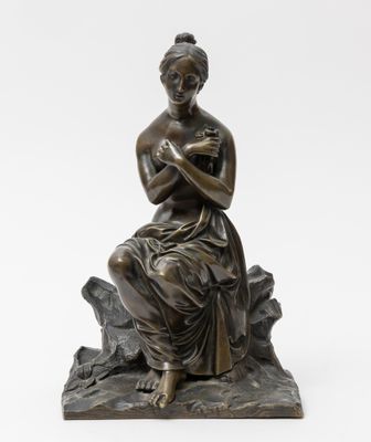 a bronze statue of a woman sitting on a rock