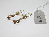 une paire de boucles d'oreilles en or avec une étiquette sur un fond blanc
