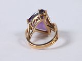 an image of a gold ring with a purple stone in it