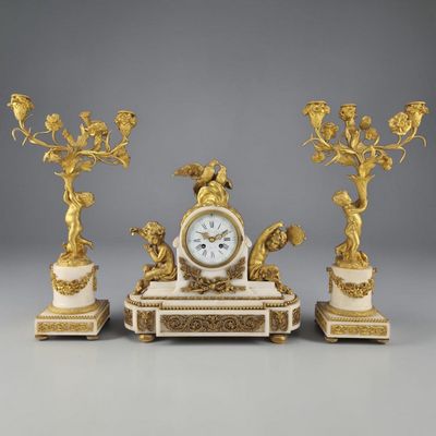 une image représentant une horloge posée sur une table, à côté de trois bougies