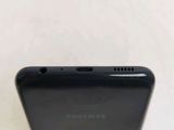 the back of a black samsung phone sitting on top of a white table