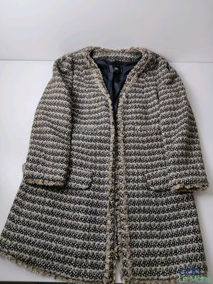 un gros plan d'un manteau tricoté posé sur une surface blanche