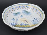 a blue and white bowl with a bird and palm trees on it