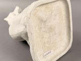 a white ceramic sculpture of a bird on a gray surface