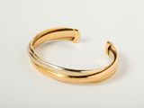 a close up of a gold cuff bracelet on a white surface