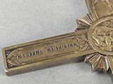 a silver cross with a red ribbon around it