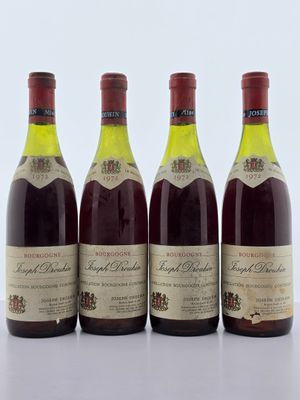 quatre bouteilles de vin sont alignées sur une surface blanche