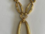 an image of a gold necklace on a white surface