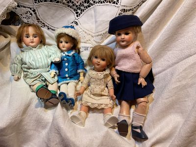 trois poupées assises ensemble sur un lit