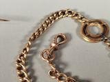 a close up of a gold chain with a watch on it