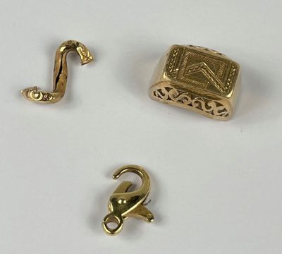 trois bijoux en or posés sur une surface blanche