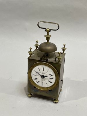 a small metal clock with a bell on top of it