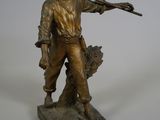 statue of a man holding a rifle and a bird on a base