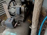 un compresseur d'air posé par terre à côté d'un arbre