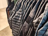 racks of jackets in a clothing store with clothes hanging on them