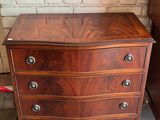 a small chest of drawers in a room with a brick wall
