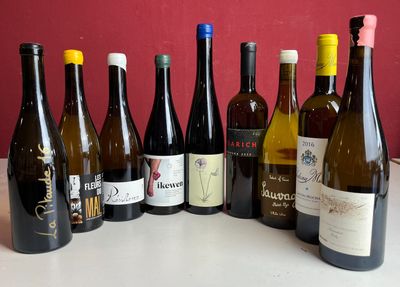 Des bouteilles de vin sont alignées sur une table devant un mur rouge.