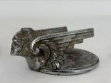 a silver statue of a winged lion on a white surface