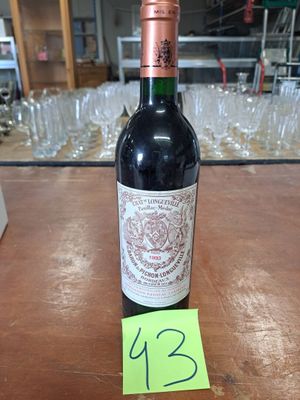 une bouteille de vin posée sur une table, avec des verres en arrière-plan