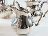 three silver teapots sitting on a white table