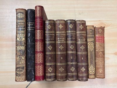 several old books are lined up on a shelf on a wooden surface