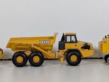 three toy construction vehicles that are lined up on a table