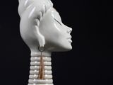 white ceramic head of a woman with a gold earring on a black background