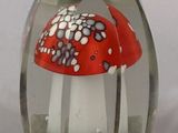 a glass vase with a red and white mushroom inside of it