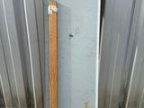 a metal box with a wooden handle next to a metal wall