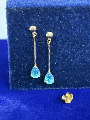 une paire de boucles d'oreilles en or ornées de cristaux bleus sur fond bleu