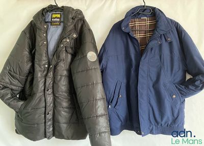 two jackets hanging on a clothes hanger on a bed