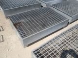 Plusieurs grilles en acier sont empilées les unes sur les autres au sol