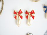 several pairs of earrings with bows and pearls on a white surface