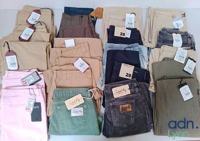 de nombreux pantalons de différentes couleurs posés sur une table, avec leurs étiquettes de prix